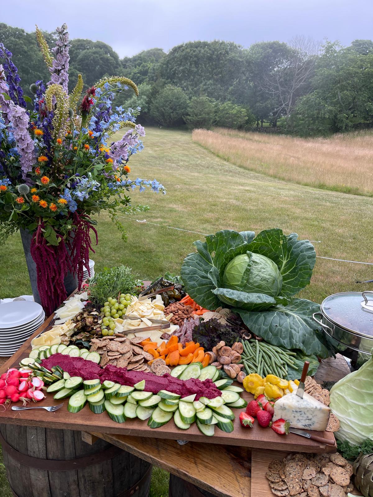 An artful arrangement of garden vegetables, ripe seasonal fruit, and artisan cheese on a marble table